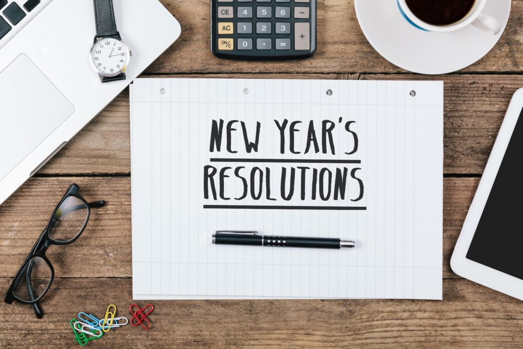 New Year's Resolutions on notepad on desk with supplies