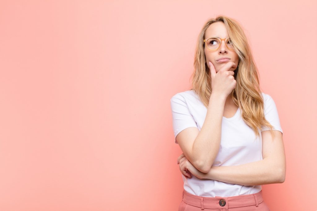 Woman wondering about Invisalign against pink background