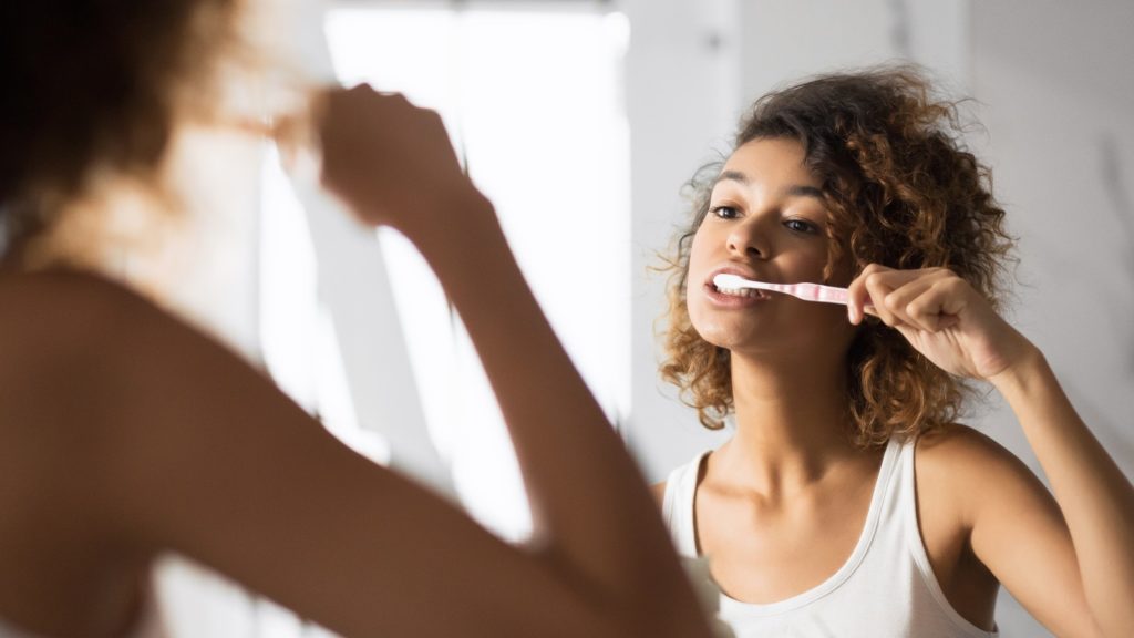 Closeup of woman with braces brushing her teeth