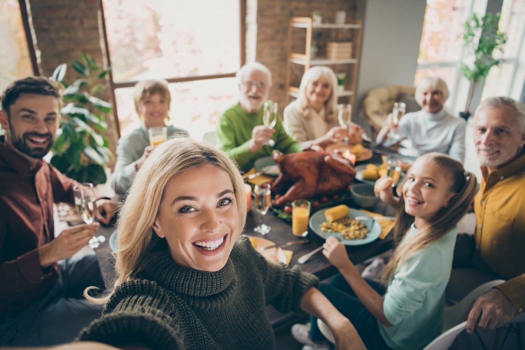Woman smiling for selfie with family at Thanksgiving