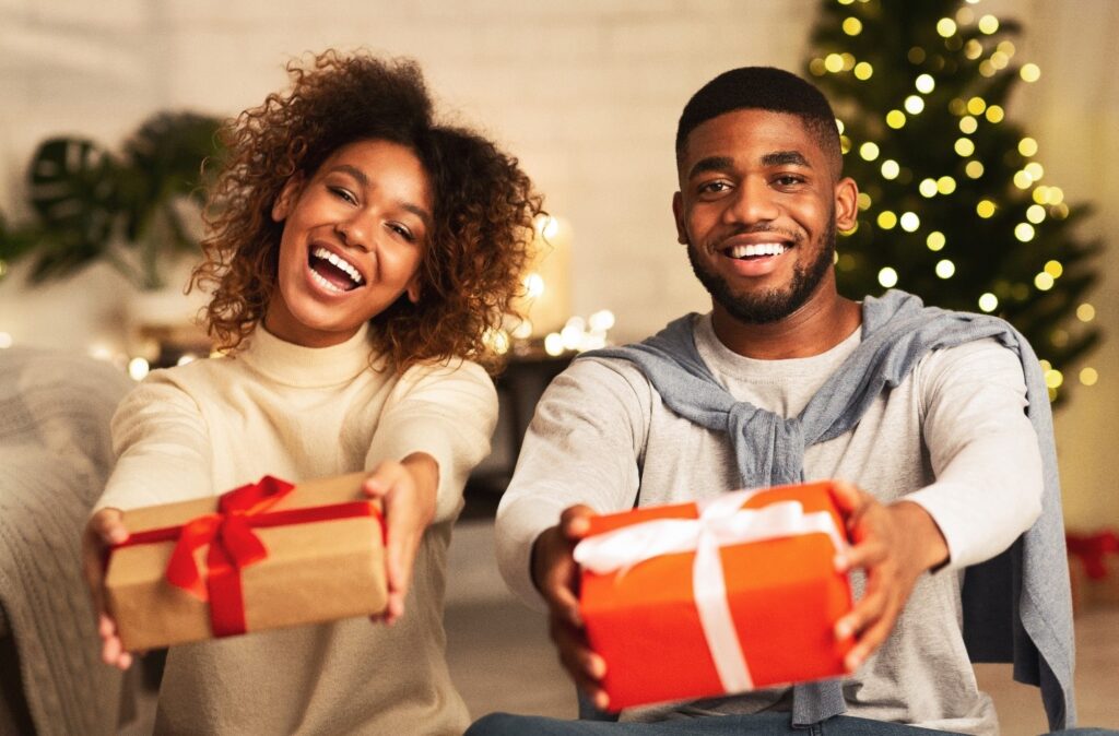 Happy couple smiling while holding wrapped gifts